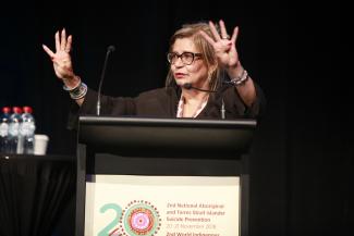 Pat Dudgeon standing behind a podium, speaking to an audience